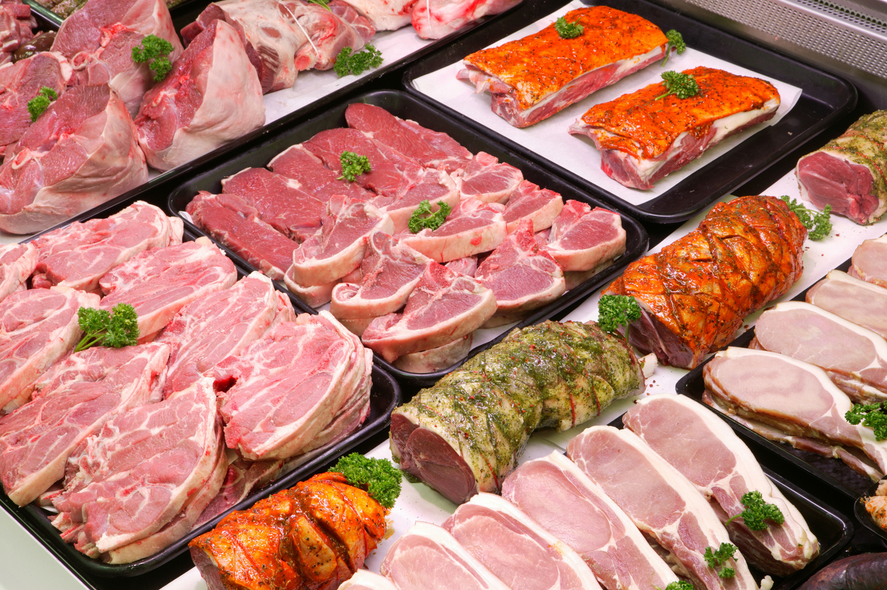 Selection of raw meat on trays in a display cooler